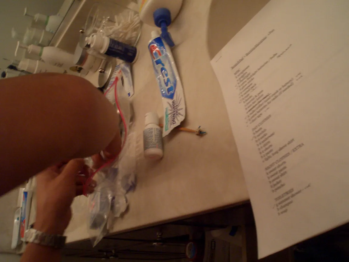 Packing toiletries into a zip bag beside the printed checklist