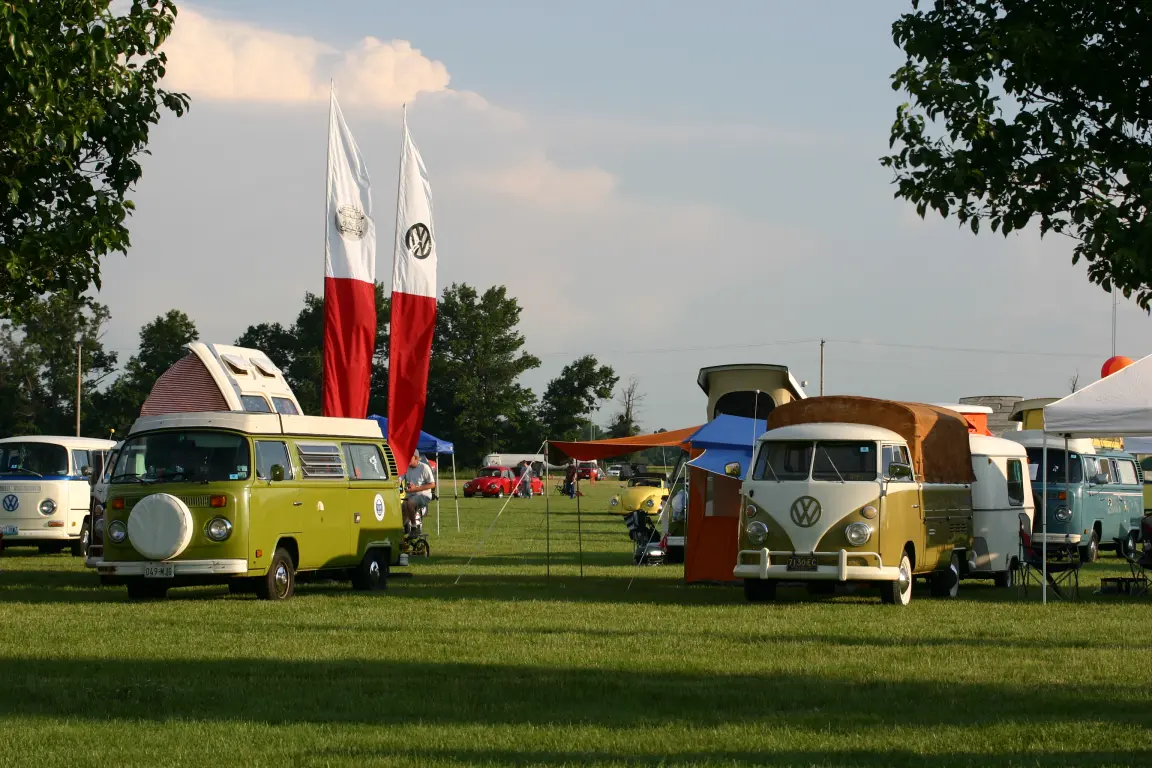 VW camper vans with pop-top roofs lined up on a grass field