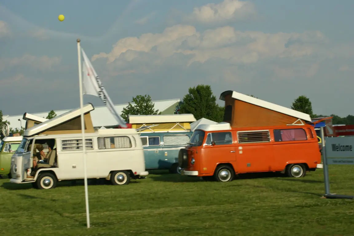 More VW campers with their pop-tops raised, a flag in the foreground