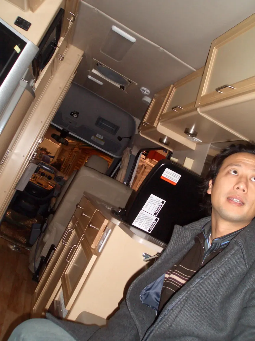 Sean inside a camper van, looking up at the cabinets